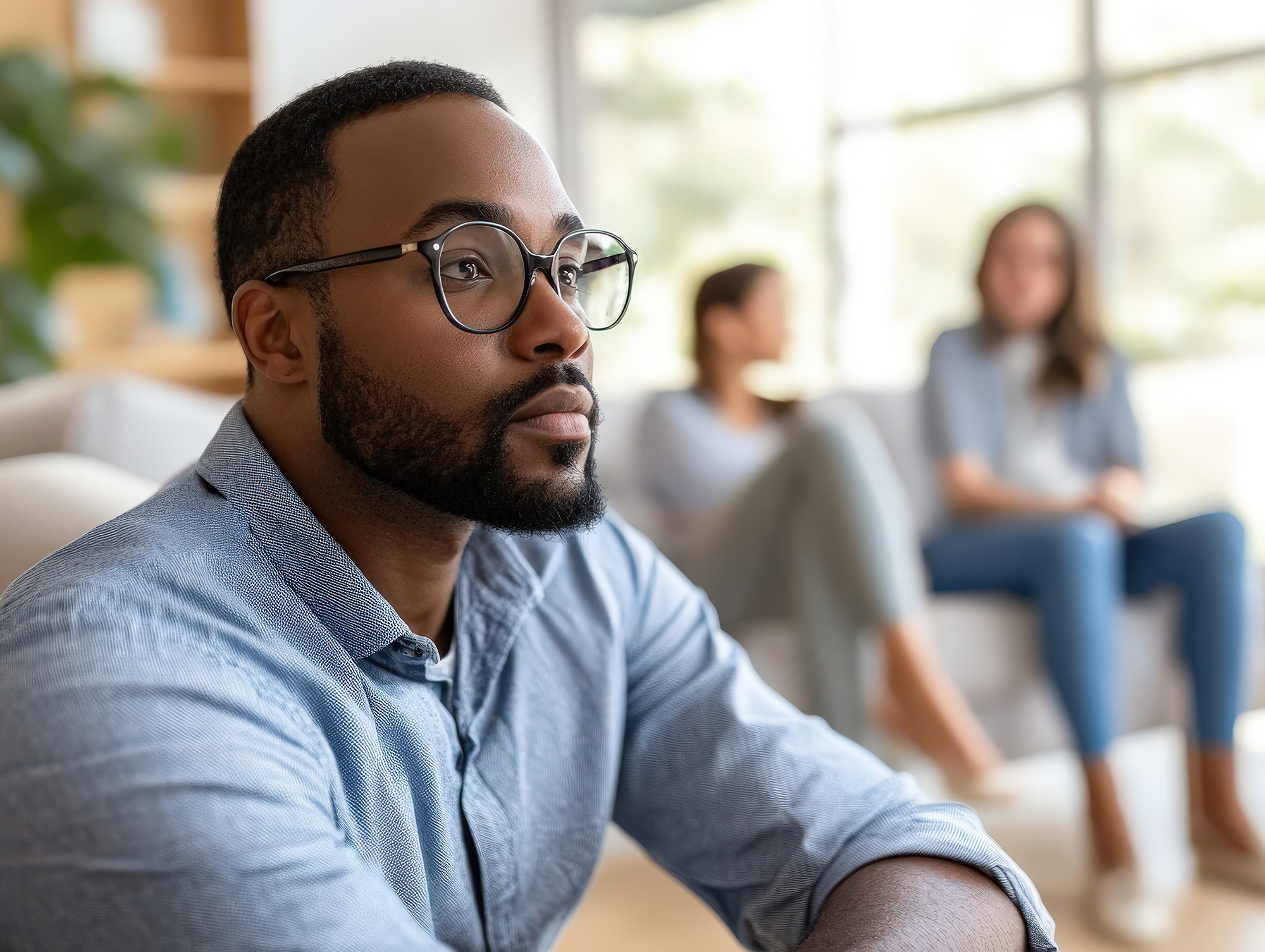 Thoughtful African American man attending a group therapy or mental health counseling session, representing MSW student training in Health/Mental Health specialization.