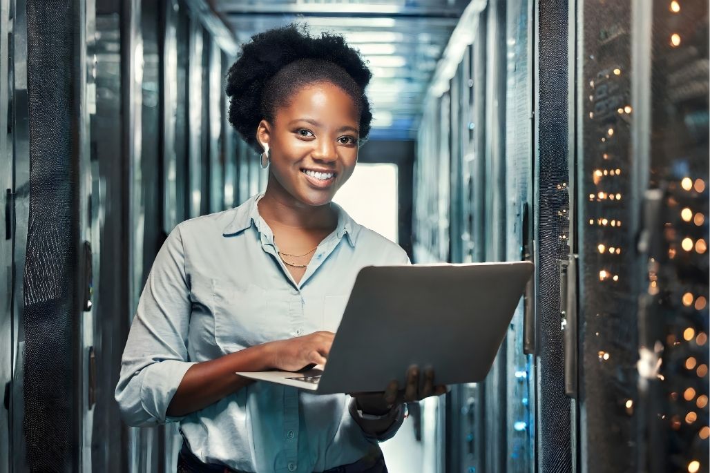 Cloud specialist using a laptop in a server room.
