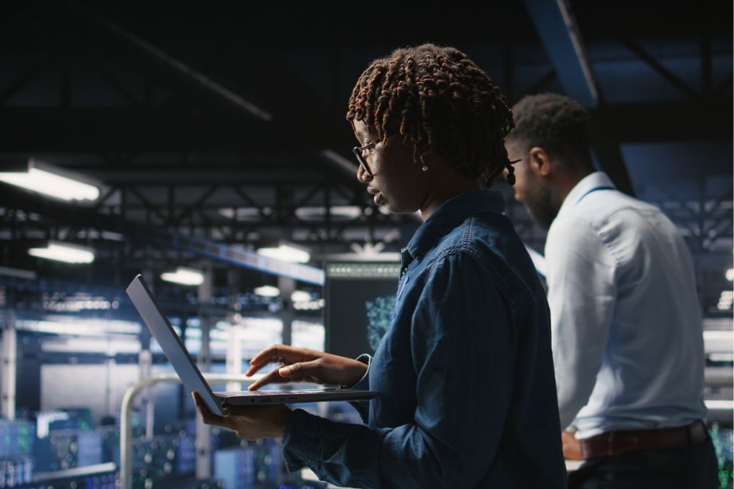 Cybersecurity analyst reviewing code on dual monitors in a lab.