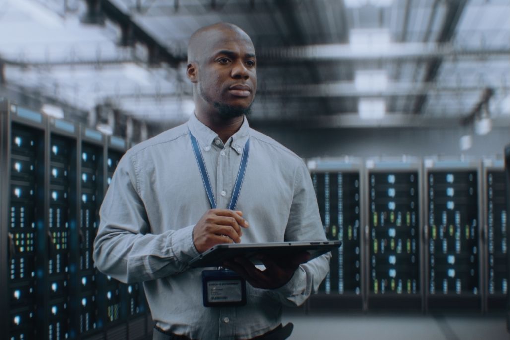 Cybersecurity analyst reviewing code on dual monitors in a lab.