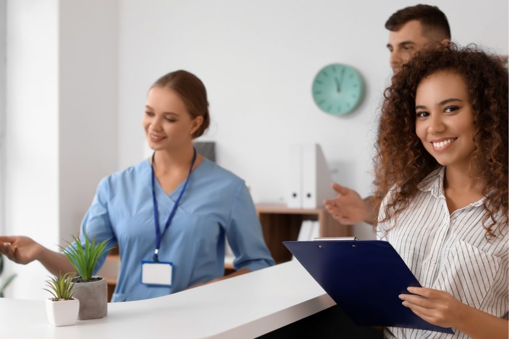 Medical office administrator reviewing patient files at a desk in a clinic.