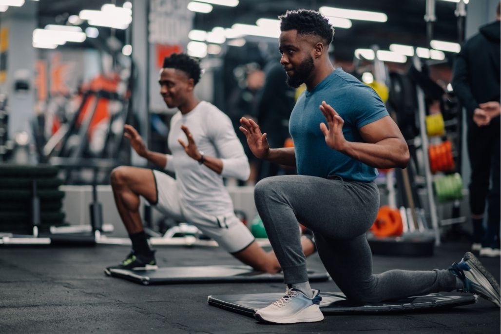 Personal trainer guiding a client through stretching exercises in a fitness center.