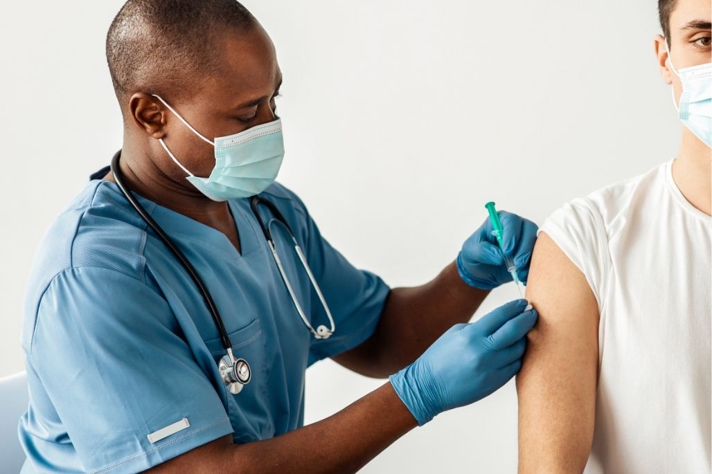 Phlebotomy technician drawing blood from a patient in a clinic.