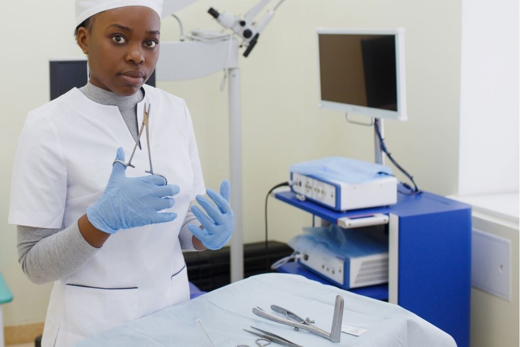 Sterile processing technician inspecting surgical instruments in a decontamination area.
